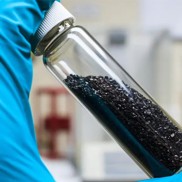 granular activated carbon charcoal vial in lab in hand blue gloves